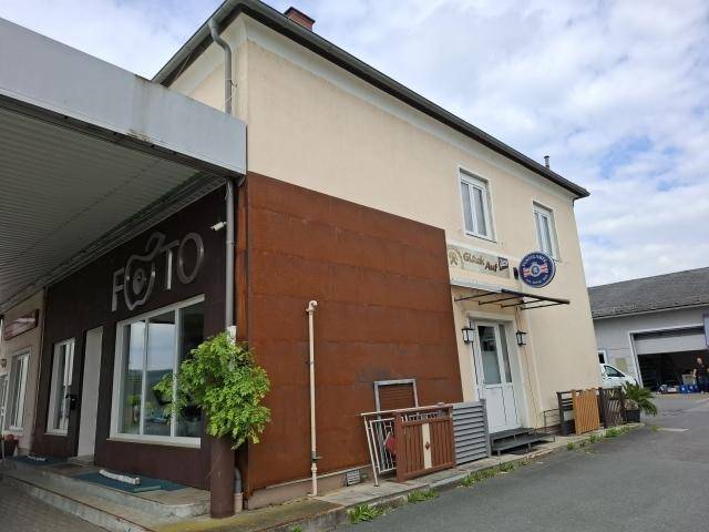 Seitenansicht eines Gebäudes mit beiger Fassade und braunen Akzenten unter bewölktem Himmel.