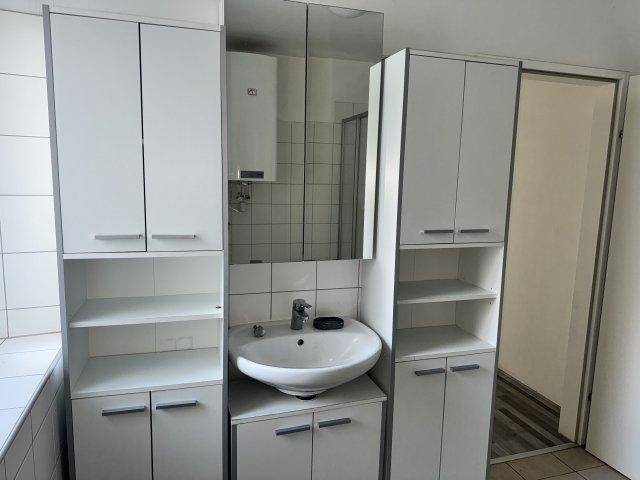 Funktionales Badezimmer mit Waschbecken, Spiegelschrank und praktischen weißen Badmöbeln.