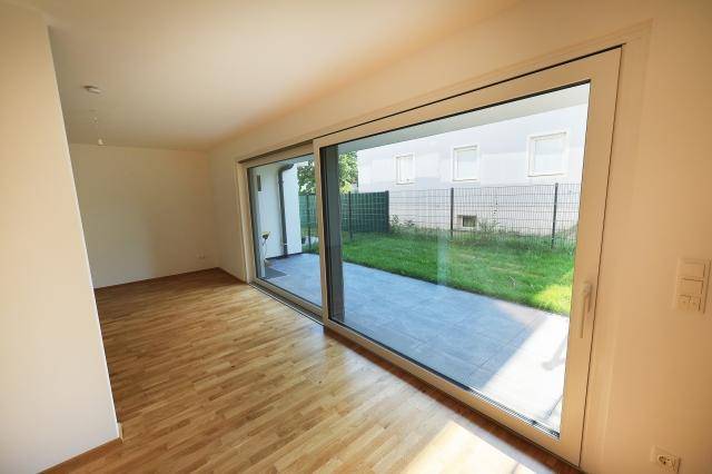 Lichtdurchfluteter Raum mit Parkettboden und großer Schiebetür zum Garten und zur Terrasse.