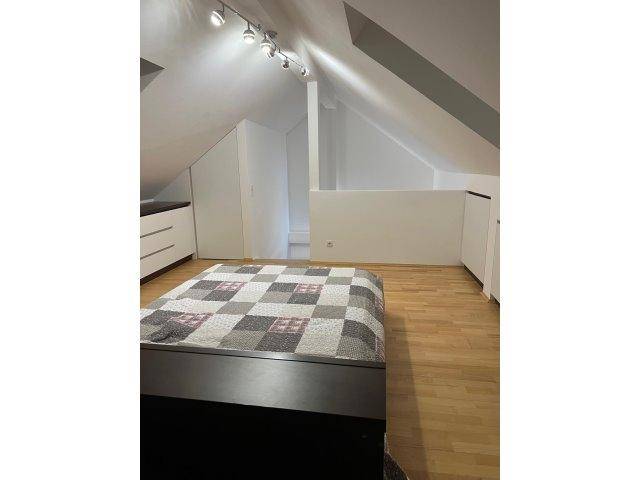 Schlafzimmer im Dachgeschoss mit Holzboden, Schrägen und minimalistischer Einrichtung.