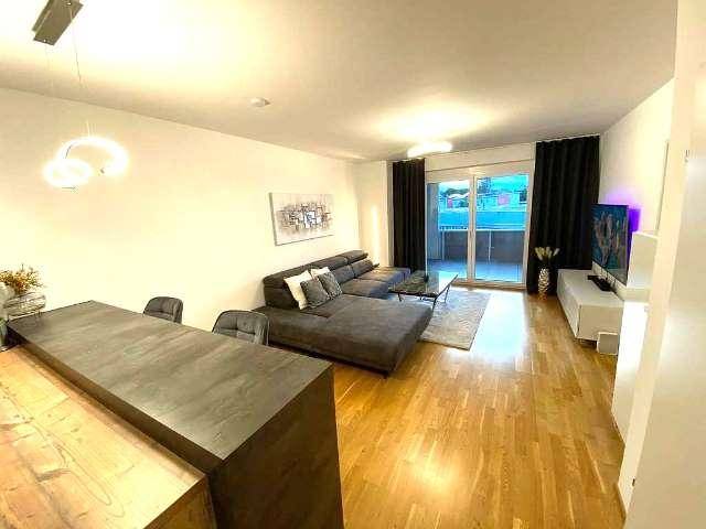 Modernes Wohnzimmer mit großem Ecksofa, Holzboden und direktem Zugang zum Balkon.