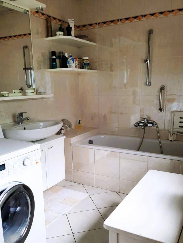 Funktionales Badezimmer mit Badewanne, Waschbecken und Waschmaschine.