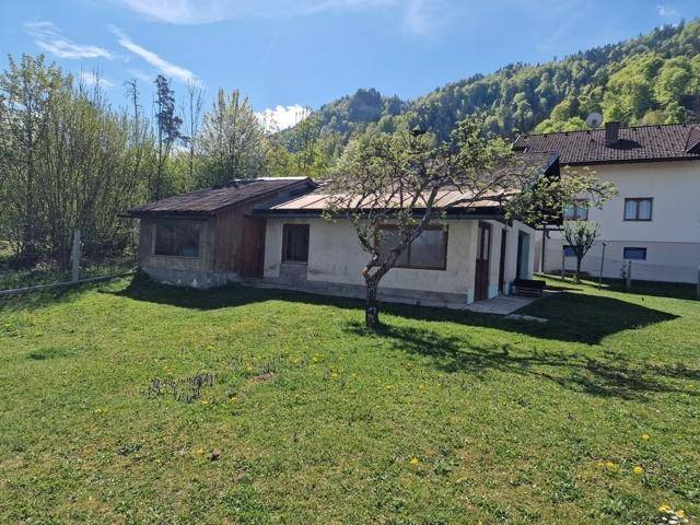 Einfamilienhaus umgeben von einer weitläufigen Grünfläche mit Blick auf bewaldete Hügel.