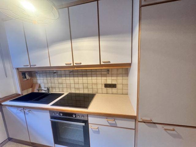 Funktionale Küche mit weißen Schränken, Induktionskochfeld und Fliesenrückwand.