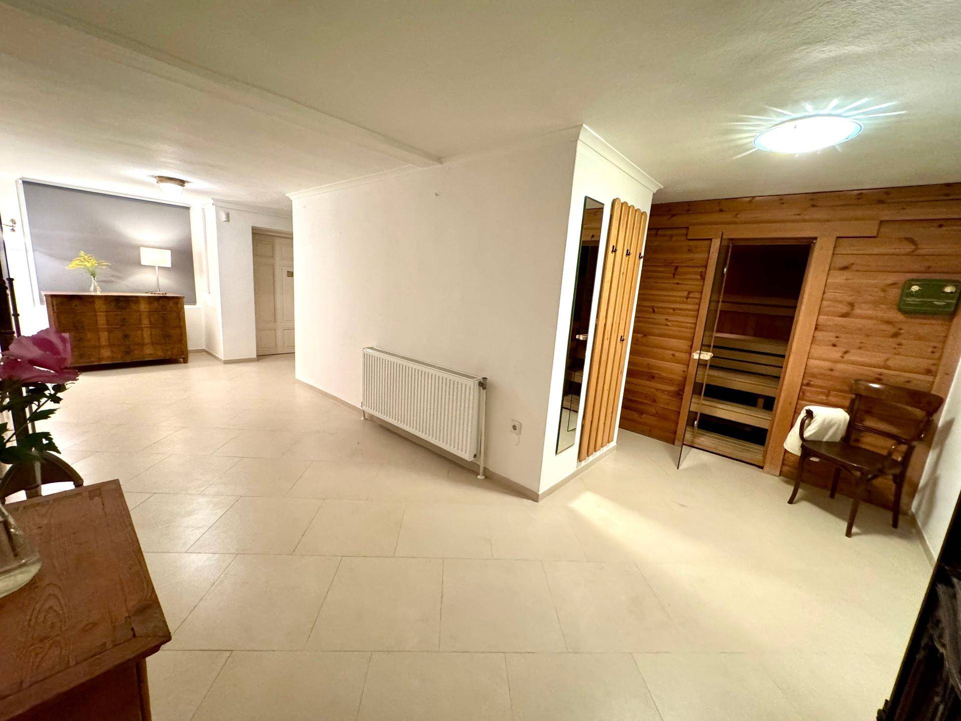 Heller Flurbereich im Untergeschoss mit Fliesenboden und sichtbarer Sauna im Hintergrund.