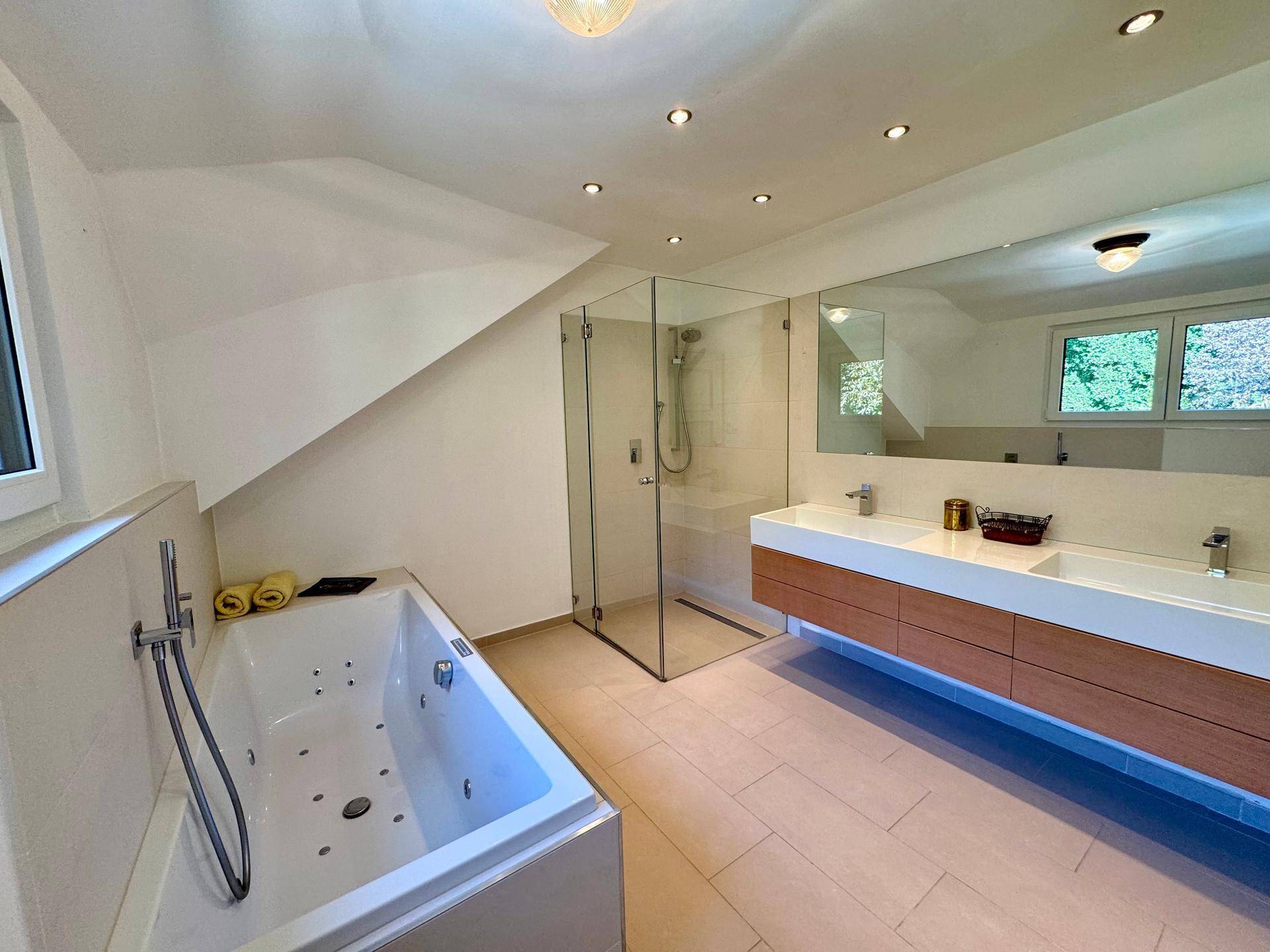 Geräumiges Badezimmer mit Doppelwaschbecken, Dusche, Badewanne und modernen Armaturen.