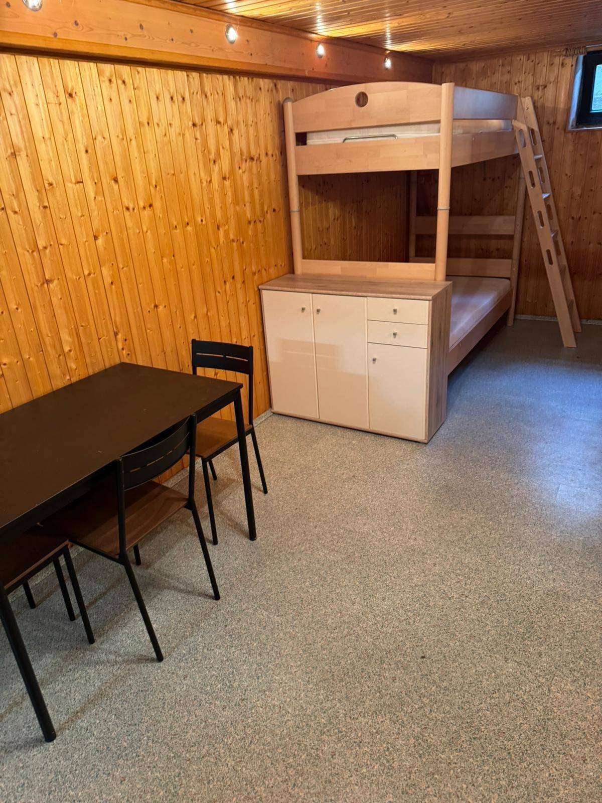 Helles Etagenbett aus Holz mit integriertem Stauraum und kleinem Esstisch.