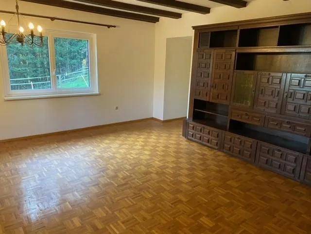 Gemütliches Wohnzimmer mit Parkettboden, sichtbaren Holzbalken und einem großen Holzschrank.