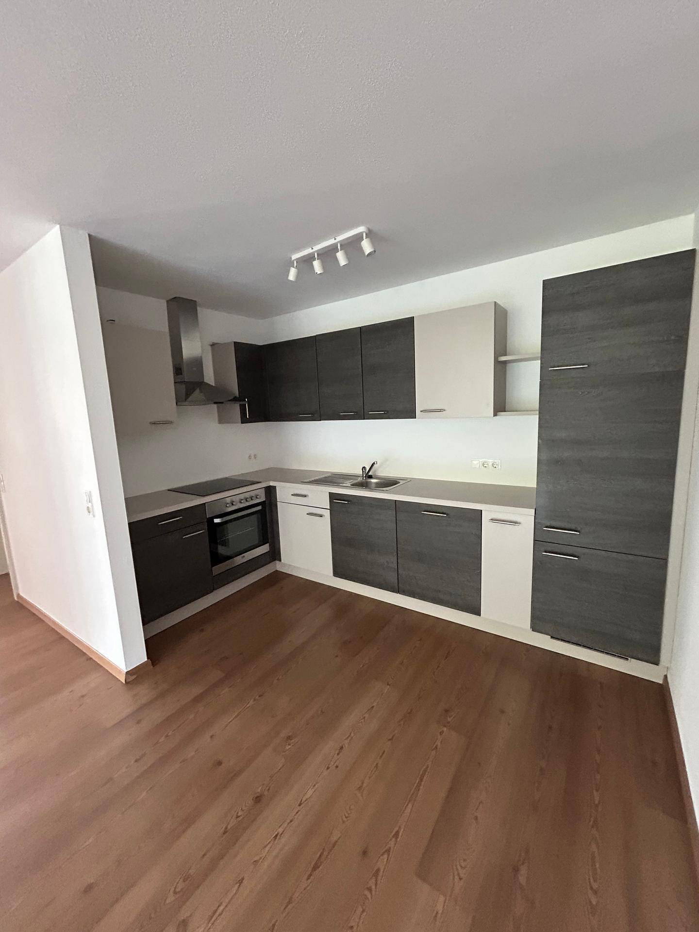 Moderne Einbauküche mit dunklen und hellen Schränken sowie integrierten Geräten.