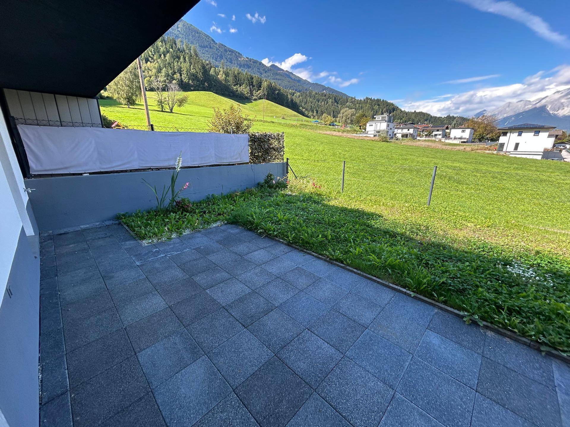 Große gepflasterte Terrasse mit Blick auf grüne Hügel und die majestätische Berglandschaft.