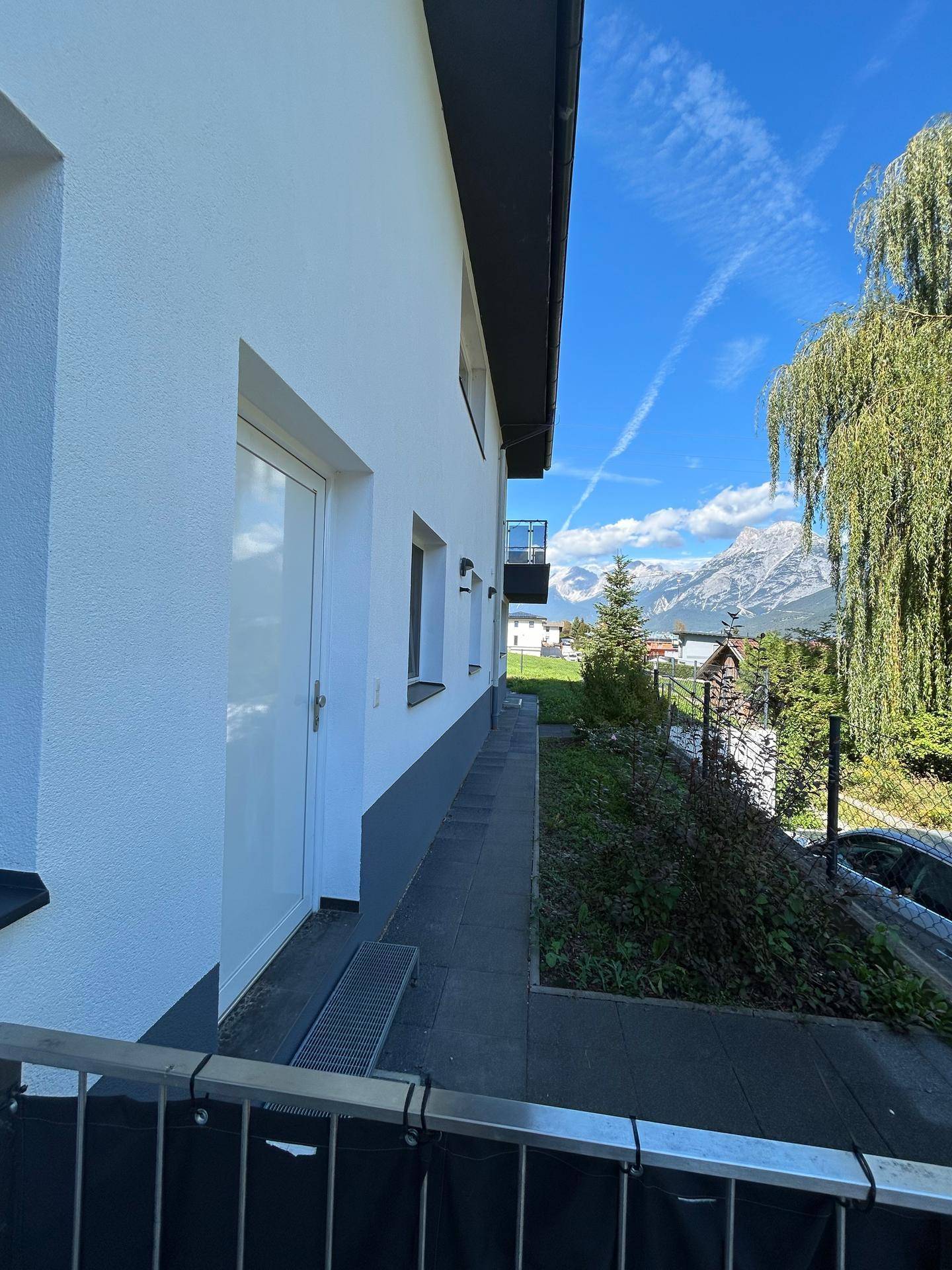 Seitenansicht des Gebäudes mit Zugang zur Terrasse und weitem Blick auf die Berge.