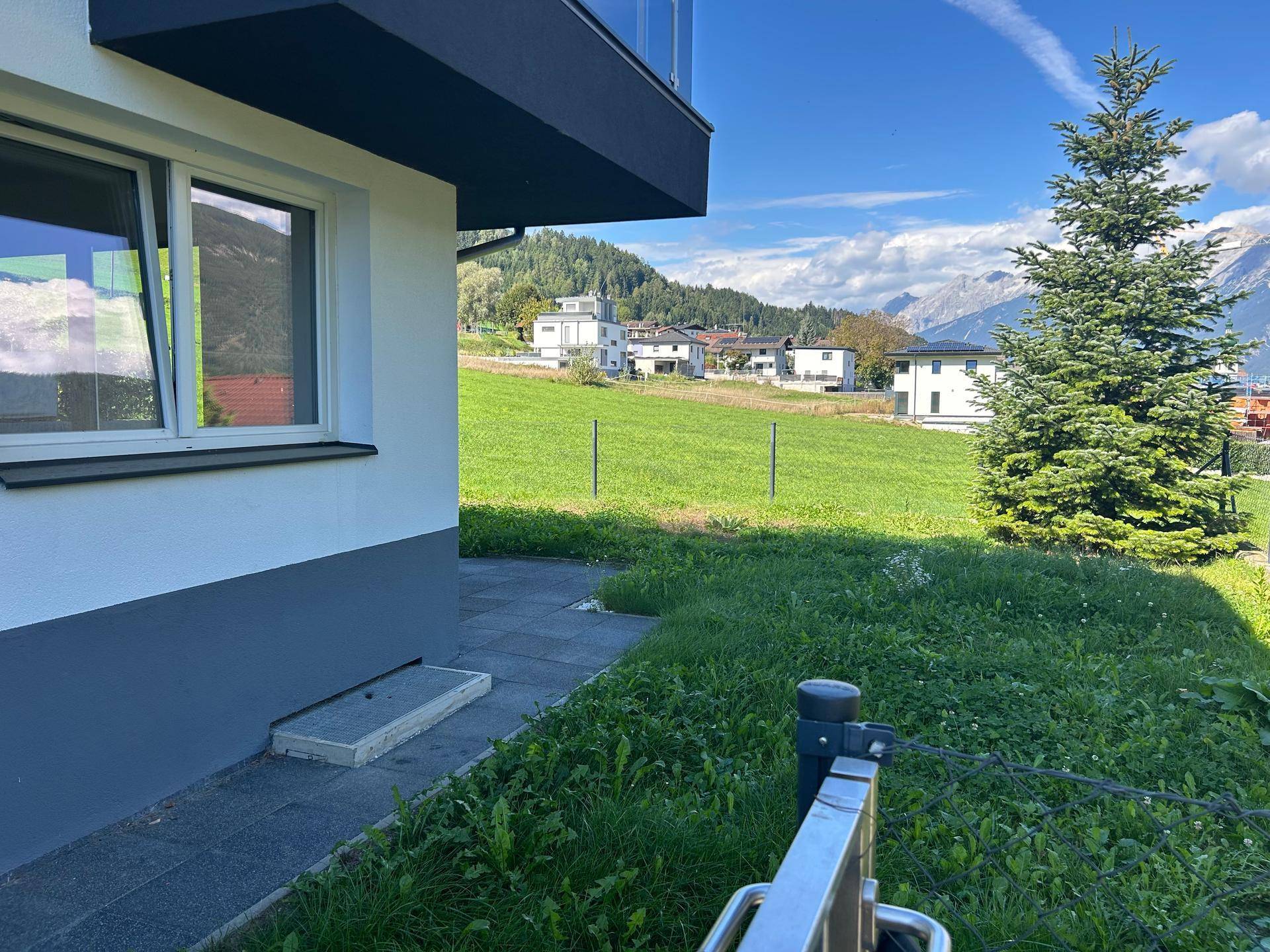 Seitenansicht des Gebäudes mit Rasenfläche und weitem Blick auf die Berge und Landschaft.