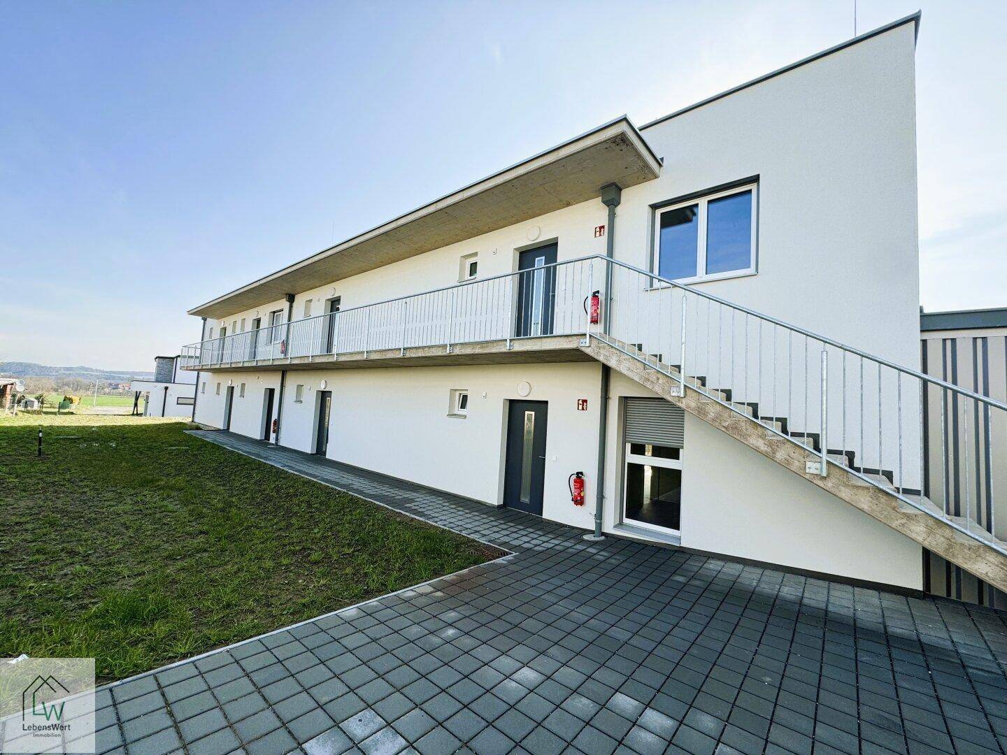 Seitenansicht des Neubaus mit Außentreppe und Zugang zu den Wohneinheiten.