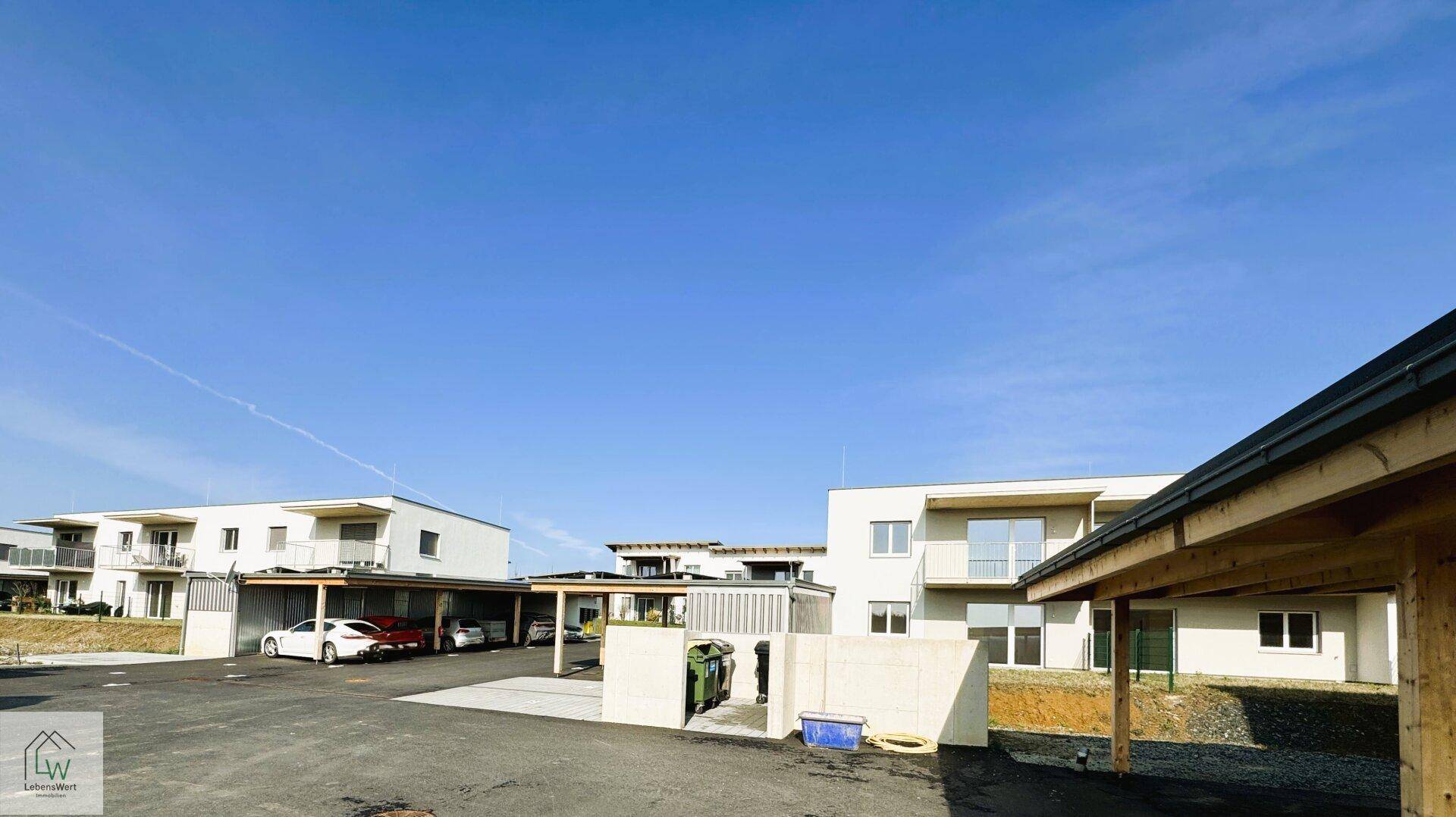 Gesamtansicht der modernen Wohnanlage mit Carports und Müllentsorgungsbereich.