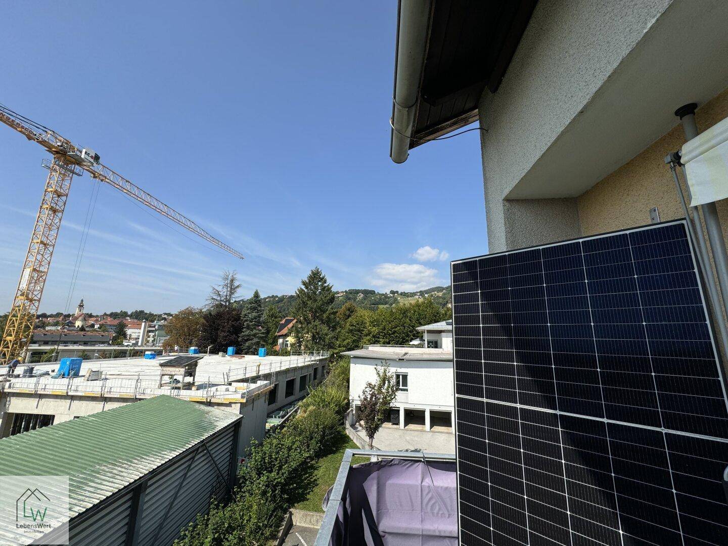 Solarmodule auf der Dachterrasse mit weitem Blick über die umliegende Stadtlandschaft.