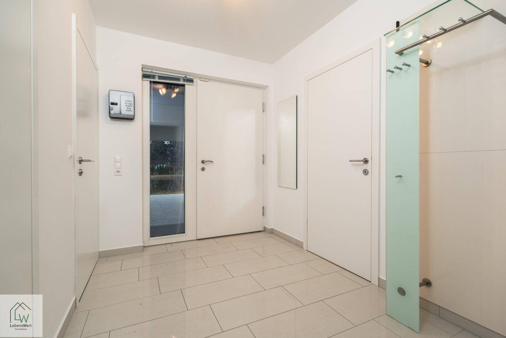 Heller Eingangsbereich mit Fliesenboden, Garderobe und viel Tageslicht.