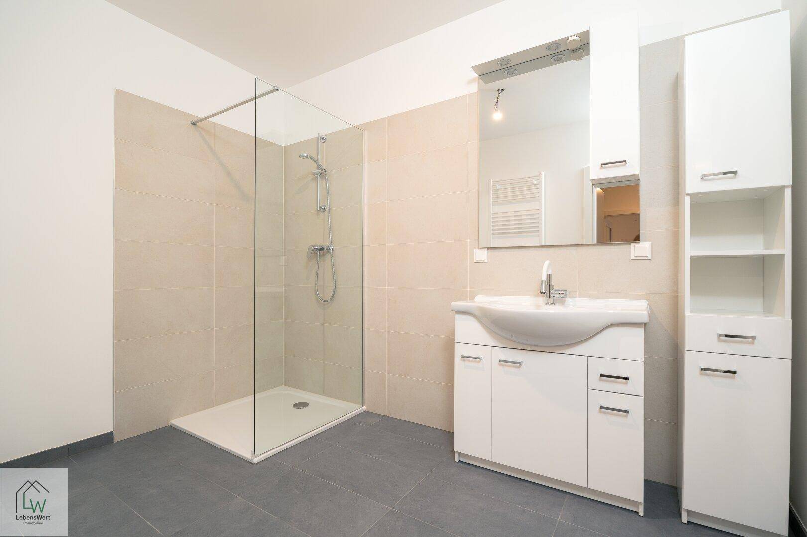 Modernes Badezimmer mit ebenerdiger Dusche, großem Waschtisch und Fliesenboden.