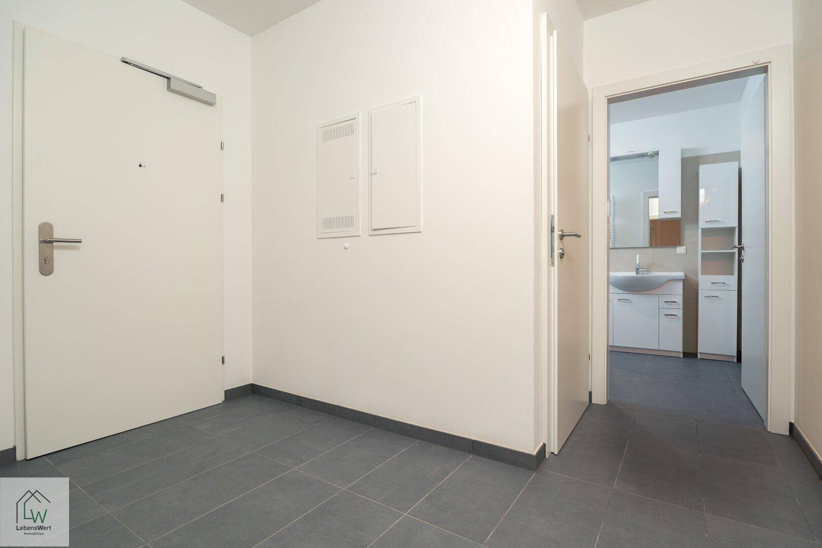 Heller Eingangsbereich mit Fliesenboden und Zugang zu Bad und weiteren Räumen.