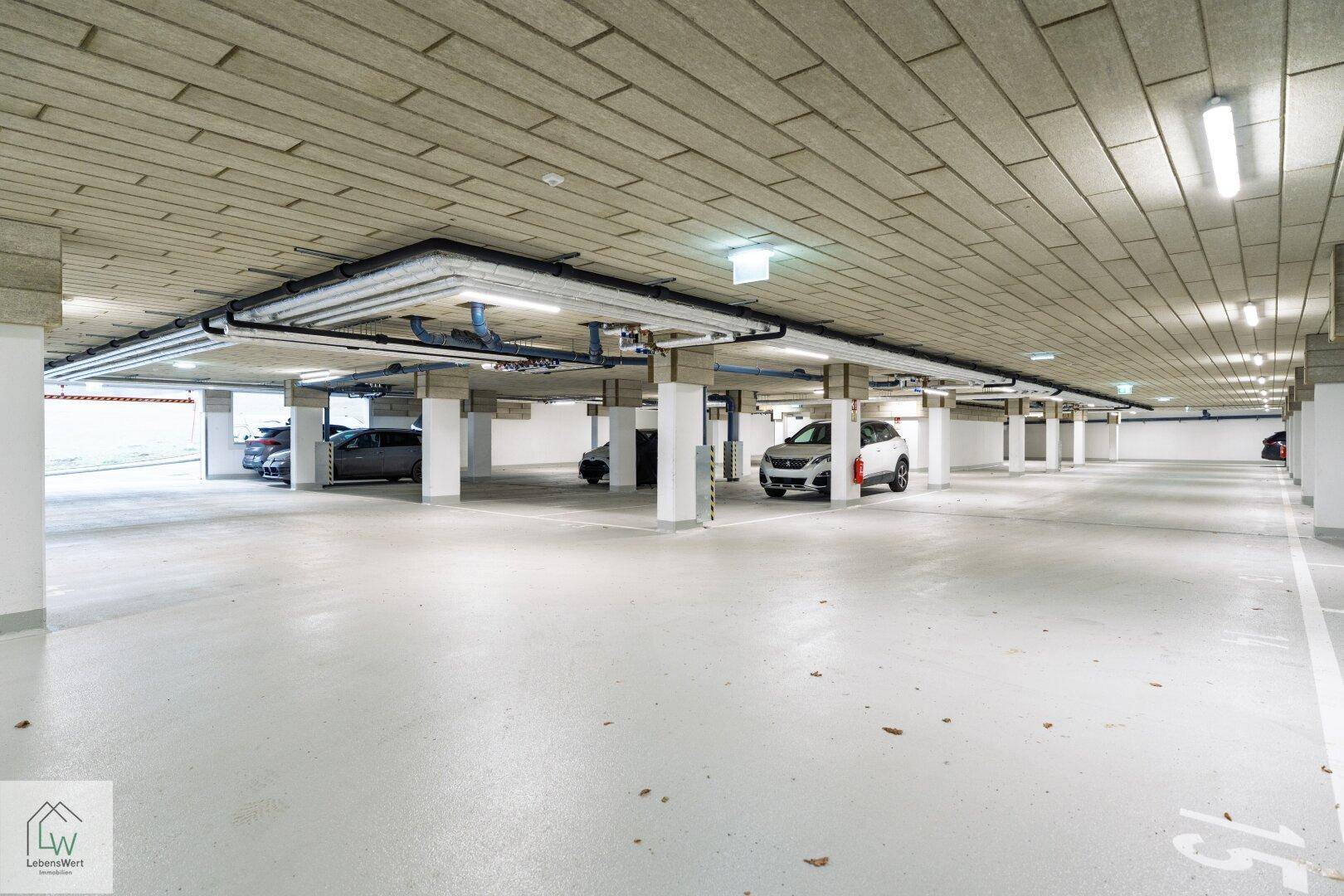Geräumige Tiefgarage mit mehreren Stellplätzen und guter Beleuchtung unter dem Gebäude.