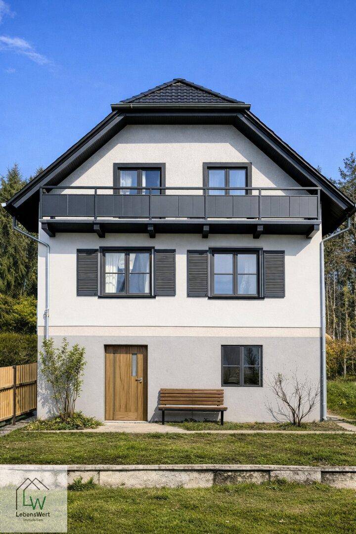 Symmetrische Fassade eines modernisierten Hauses mit Balkon und dunklen Fensterläden.