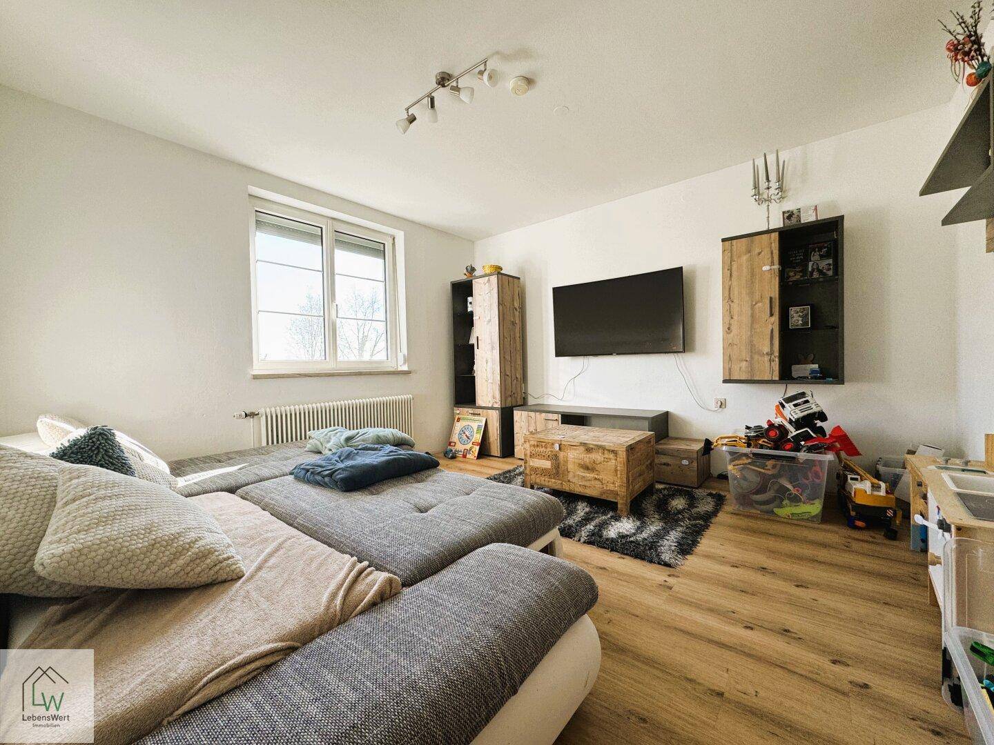 Gemütliches Wohnzimmer mit großem Sofa, Holzmöbeln und Laminatboden.