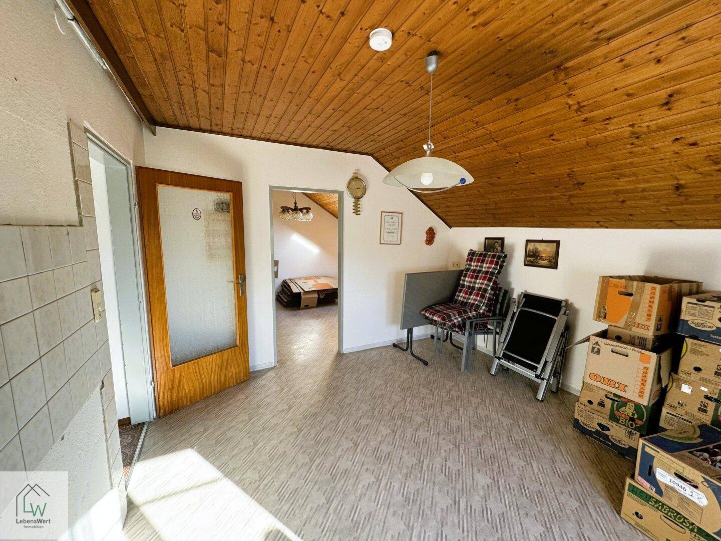 Dachgeschossraum mit Holzdecke, Laminatboden und Stauraum.