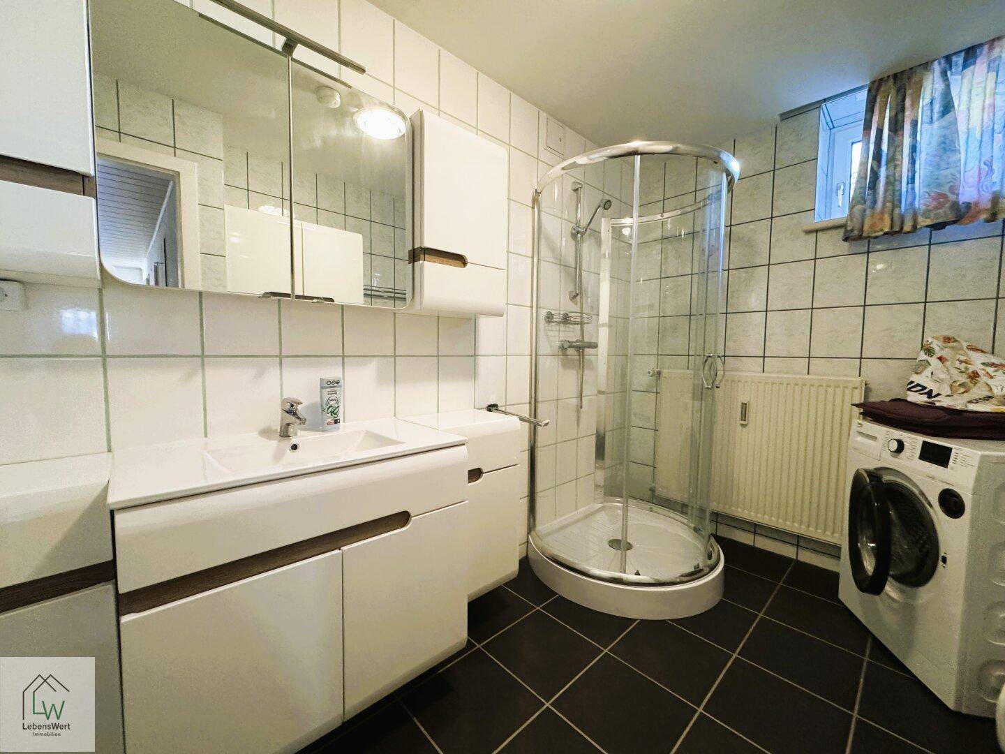 Modernes Badezimmer mit Duschkabine, Waschbecken und Waschmaschine.