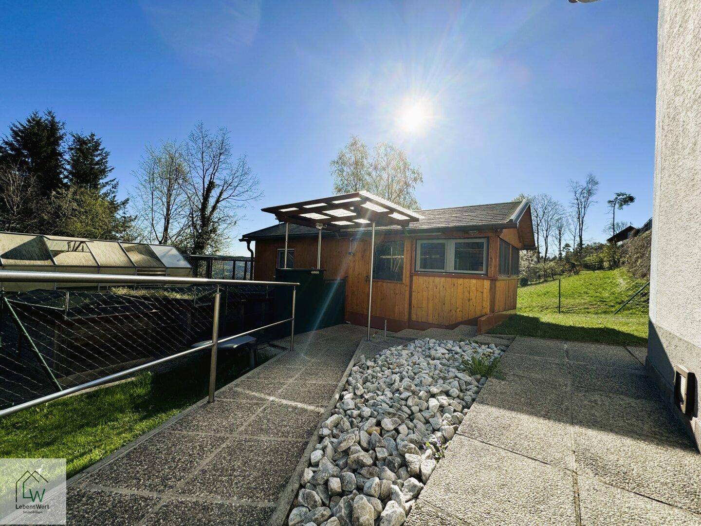 Weg führt zu einem charmanten Gartenhaus mit Steingarten und sonniger Umgebung.