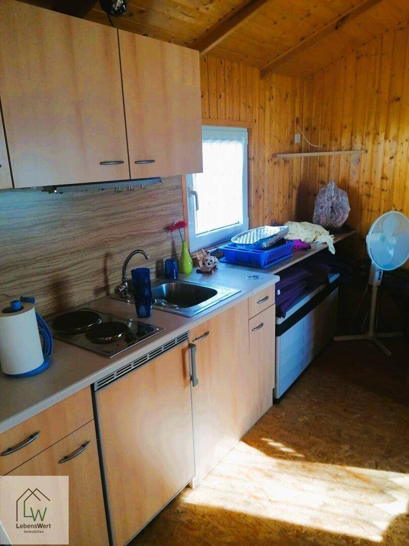 Kleine Küchenzeile im Gartenhaus mit Holzverkleidung und einfacher Ausstattung.