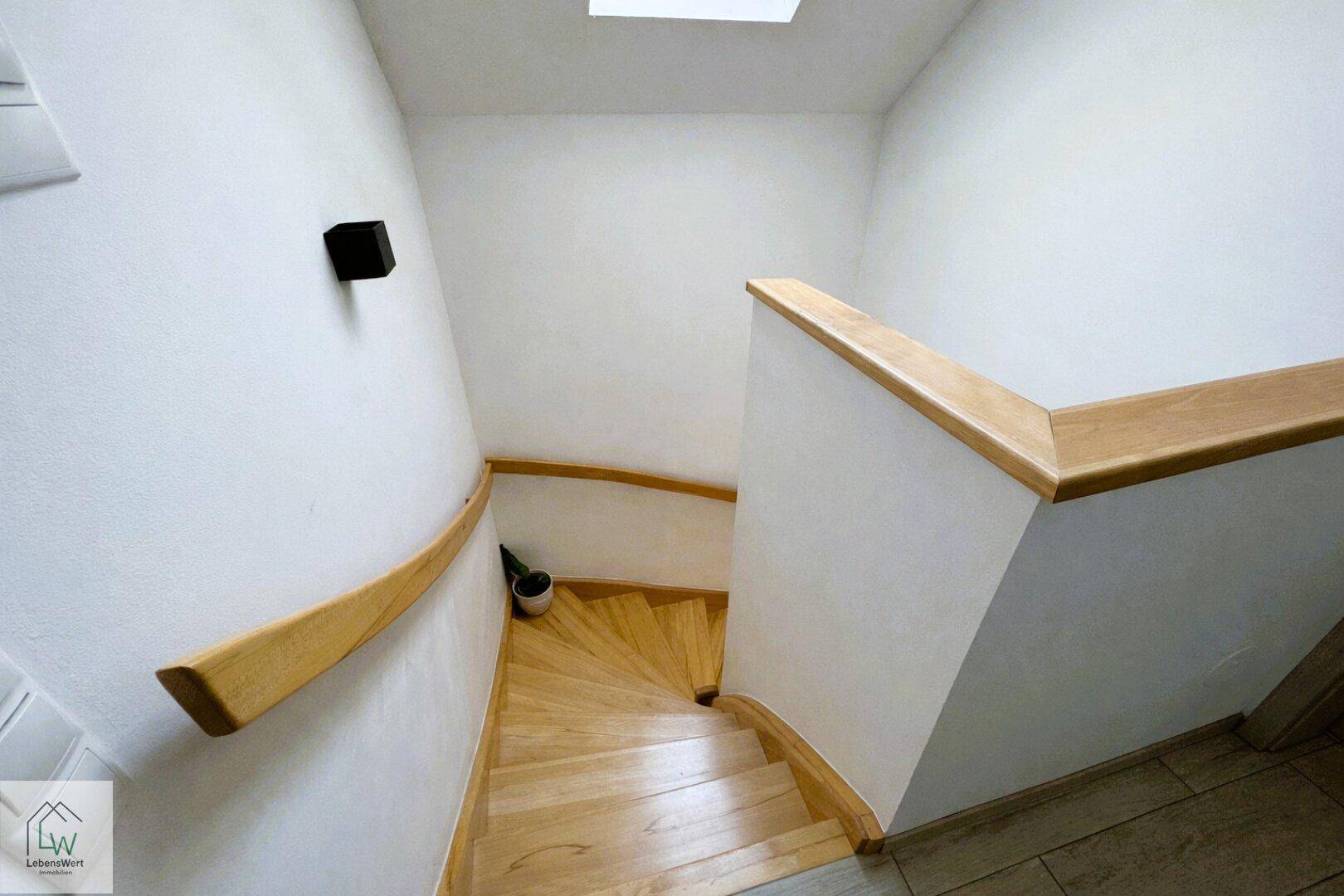 Holztreppe mit hellem Geländer, die die Stockwerke des Hauses miteinander verbindet.