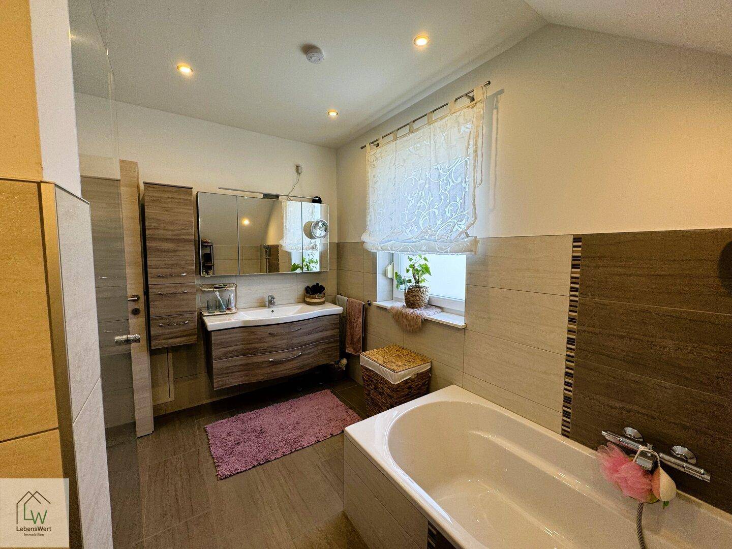 Helles Badezimmer mit modernem Waschtisch, Badewanne und Fenster für natürliche Belüftung.