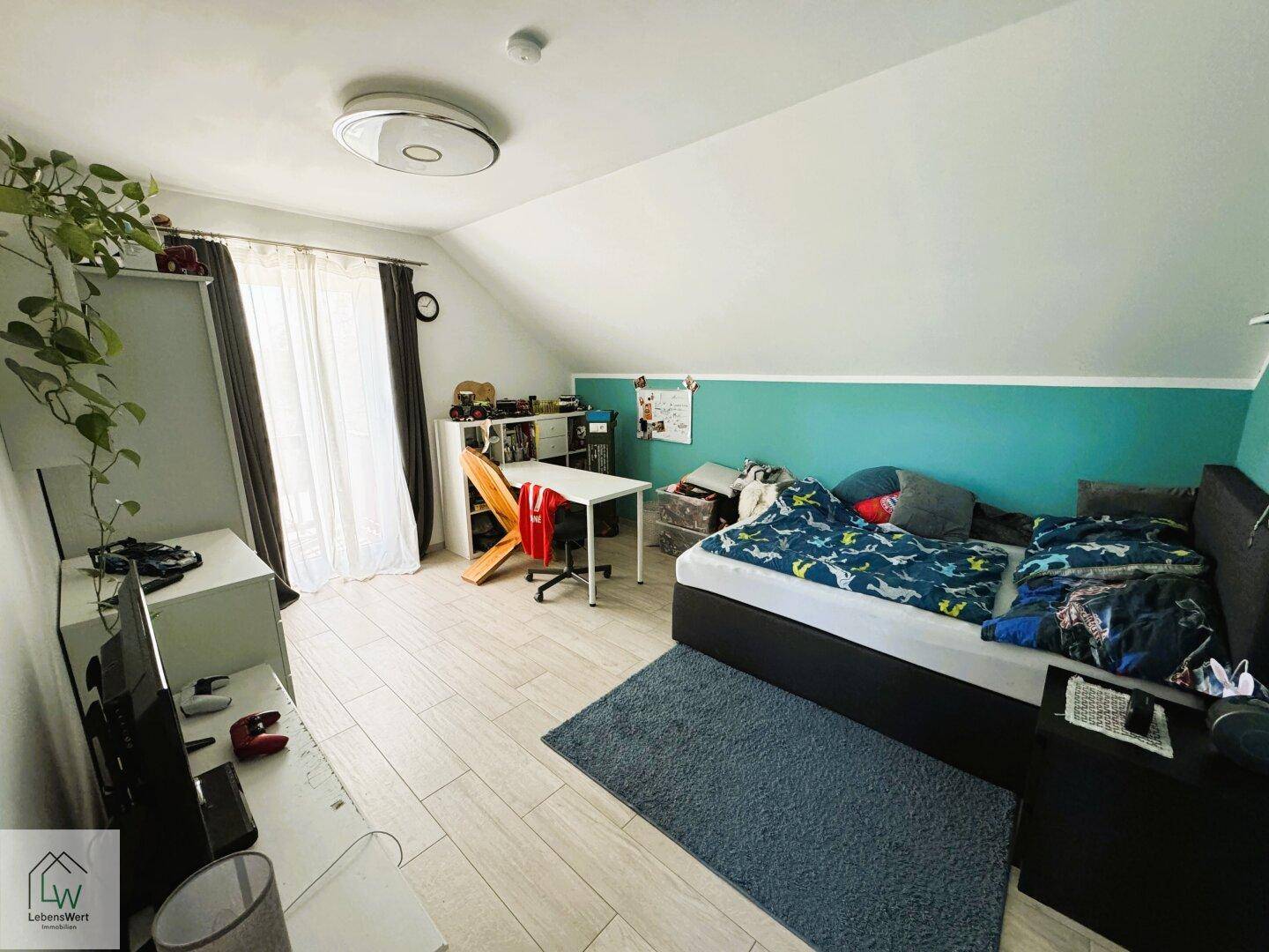 Kinderzimmer mit hellem Fliesenboden, farbiger Wand und ausreichend Platz zum Spielen und Lernen.