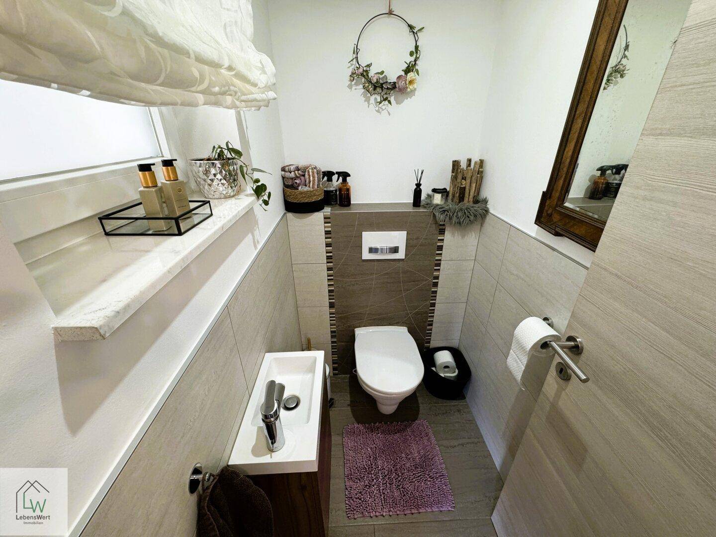 Kleines Gäste-WC mit modernem Wand-WC, Handwaschbecken und Fenster.