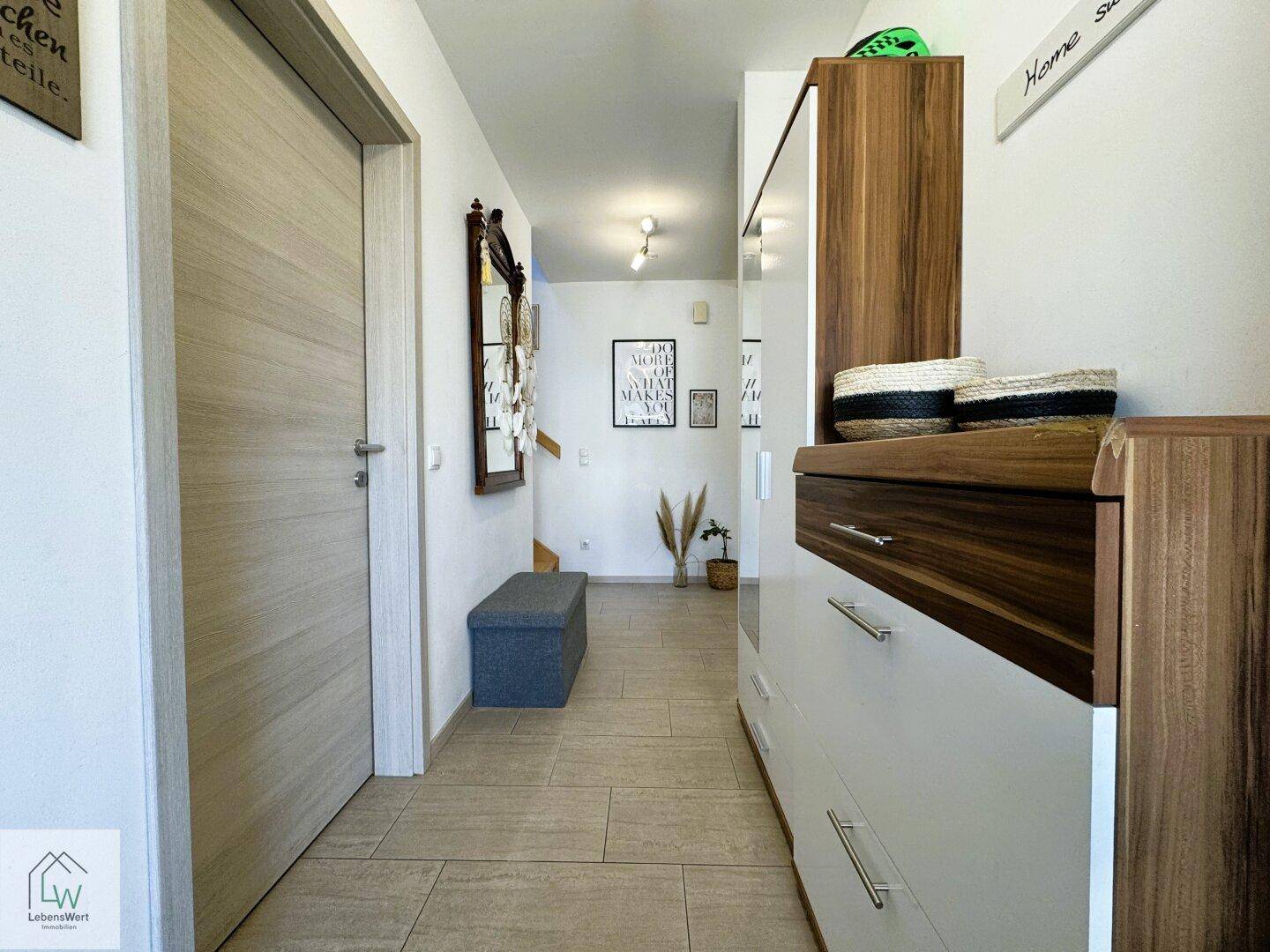 Heller Eingangsbereich mit Fliesenboden, Garderobe und dekorativen Elementen.