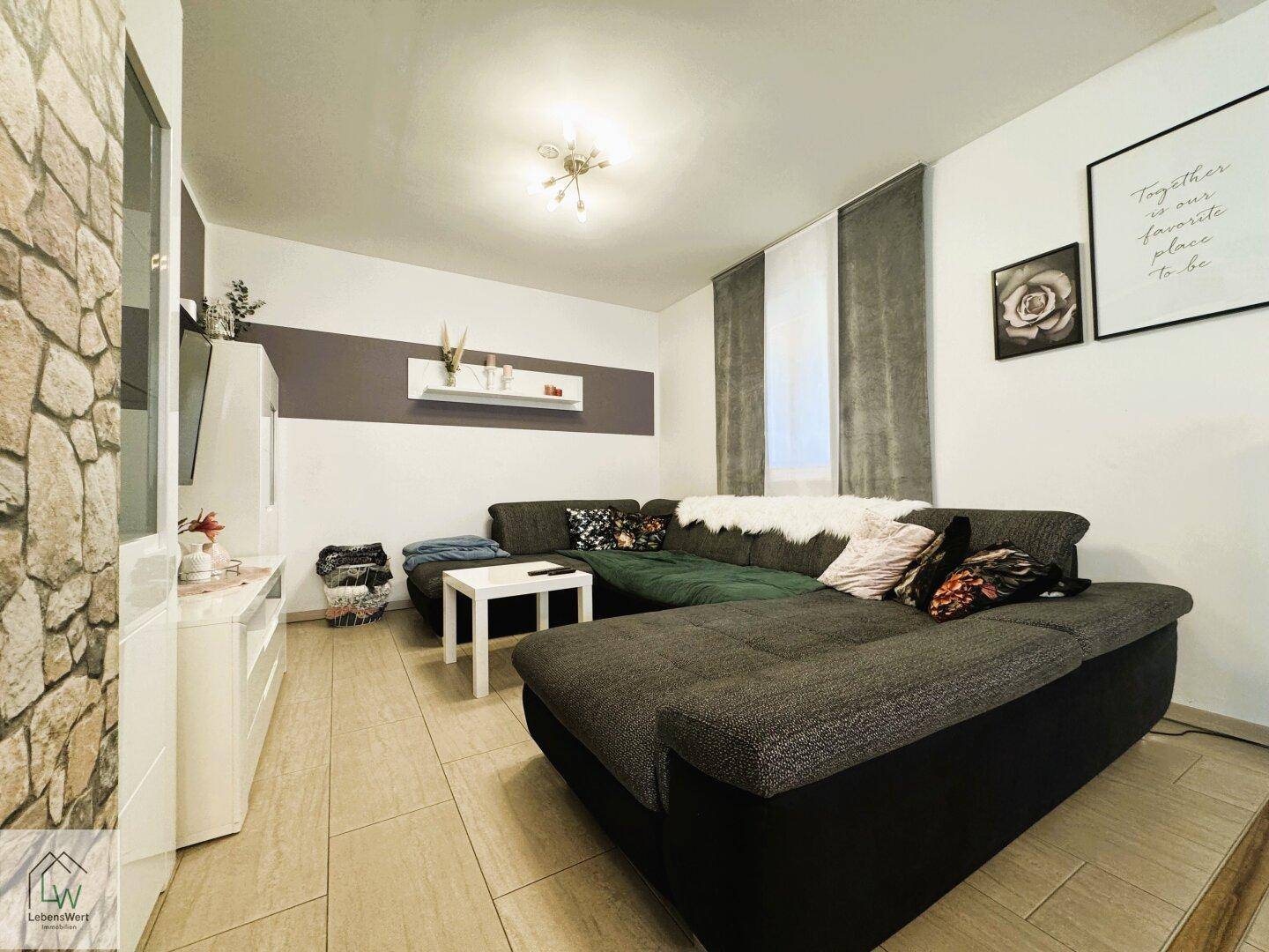 Gemütliches Wohnzimmer mit großem Ecksofa, Steinwandakzent und modernen Dekorationselementen.