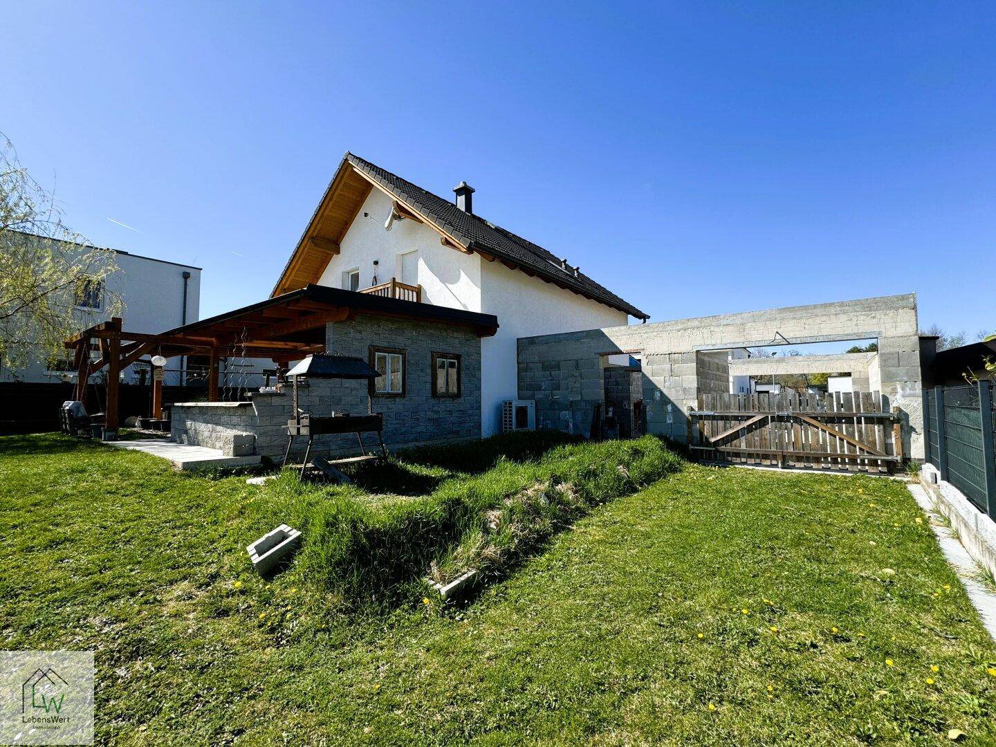 Weitläufiger Gartenbereich hinter dem Haus mit Rasen und angrenzender Baustelle.