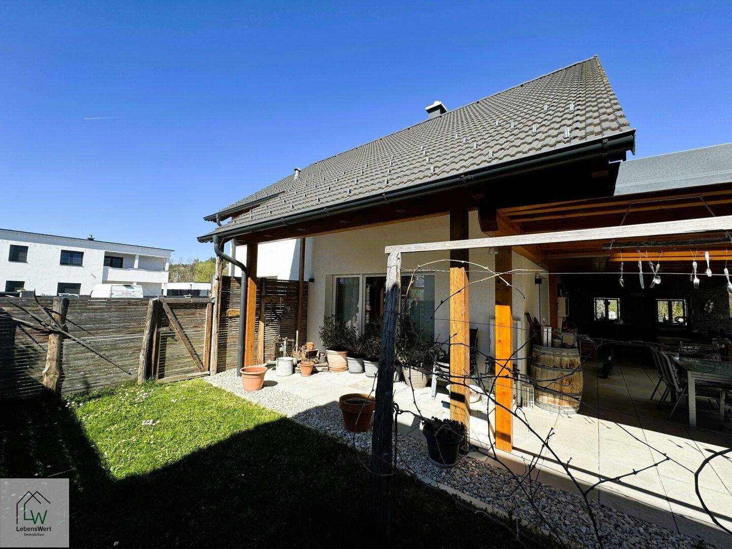 Seitenansicht des Hauses mit überdachter Terrasse und angrenzendem Gartenbereich.