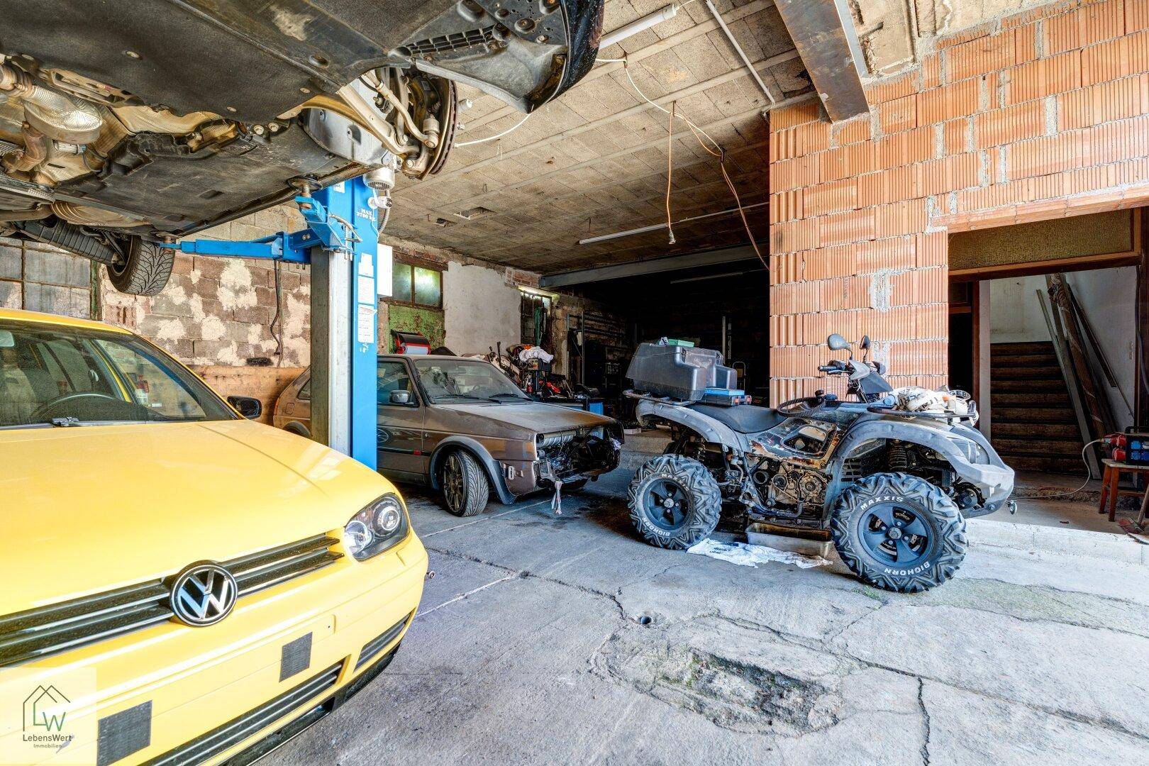 Detailansicht der Werkstatt mit einem Auto auf der Hebebühne und einem Quad am Boden.