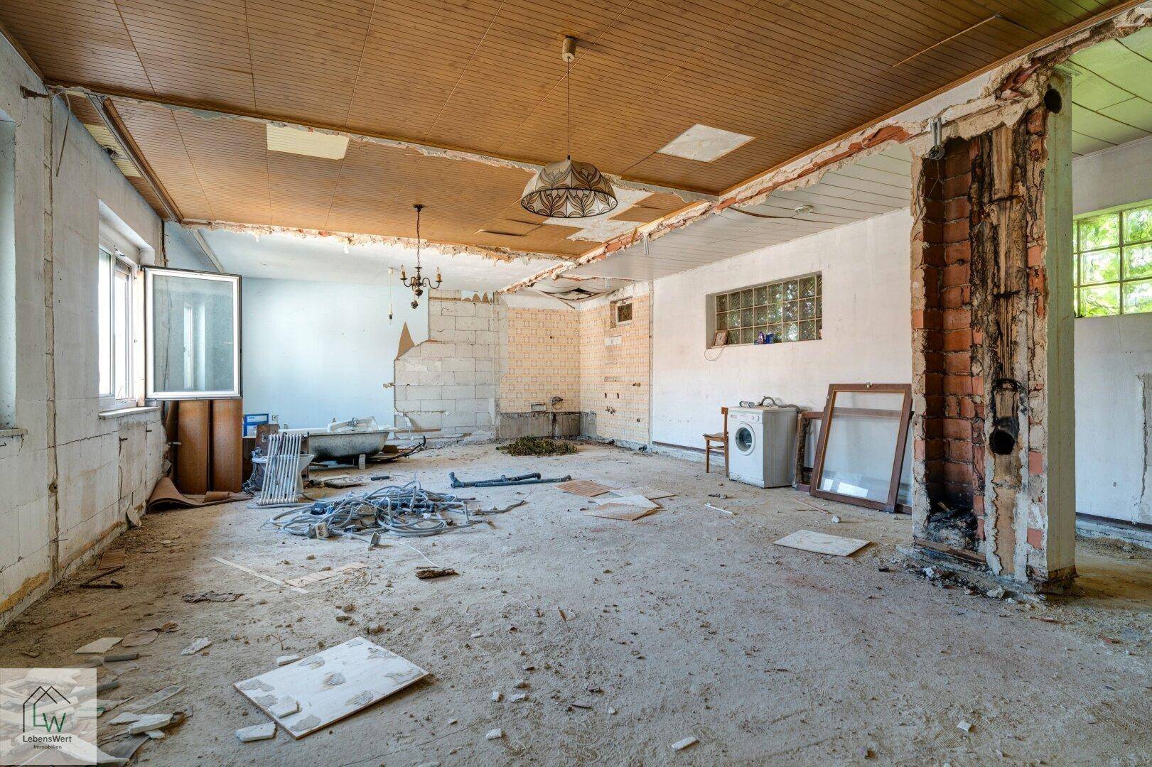 Weitläufiger Raum in Renovierung mit freigelegten Wänden und Deckenverkleidung.
