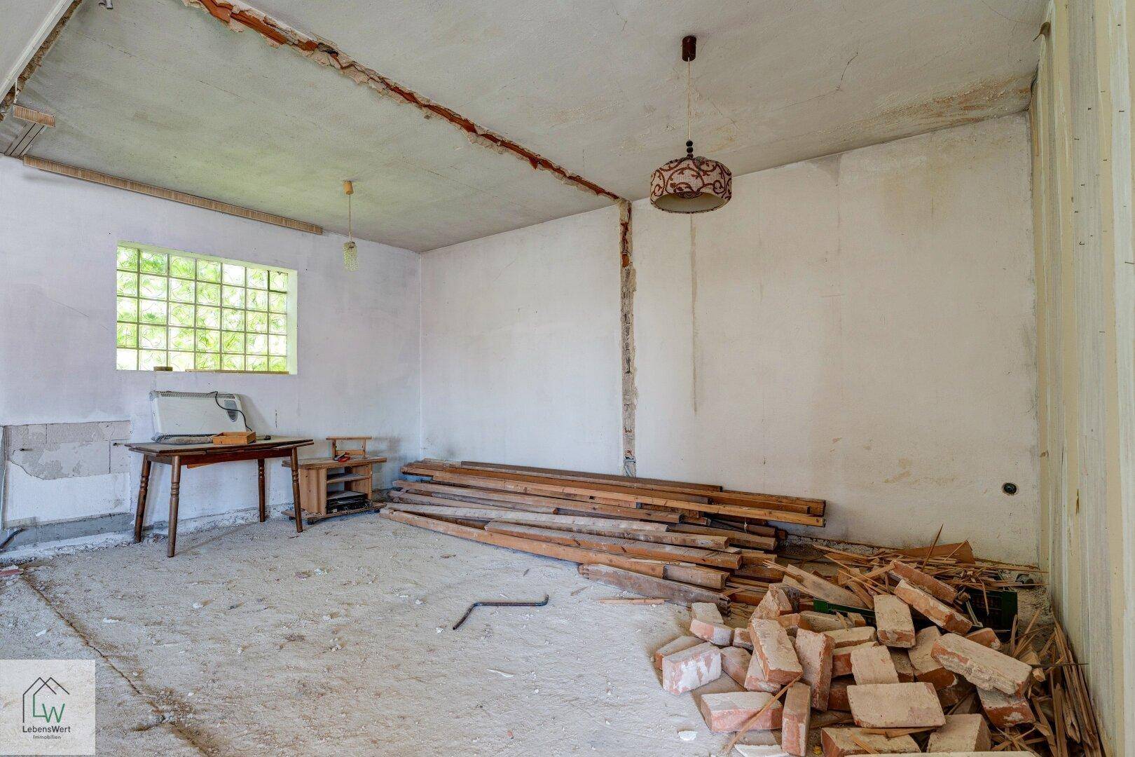 Raum in Sanierung mit Ziegelresten und Holzstapeln, bereit für den Umbau.