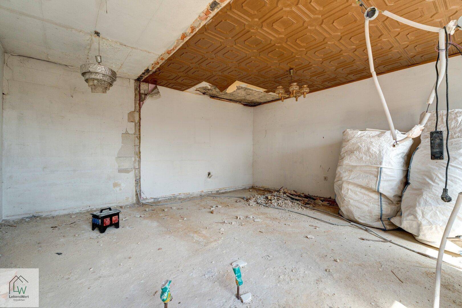 Raum in Renovierung mit dekorativer Deckenverkleidung und großen Säcken mit Baumaterial.