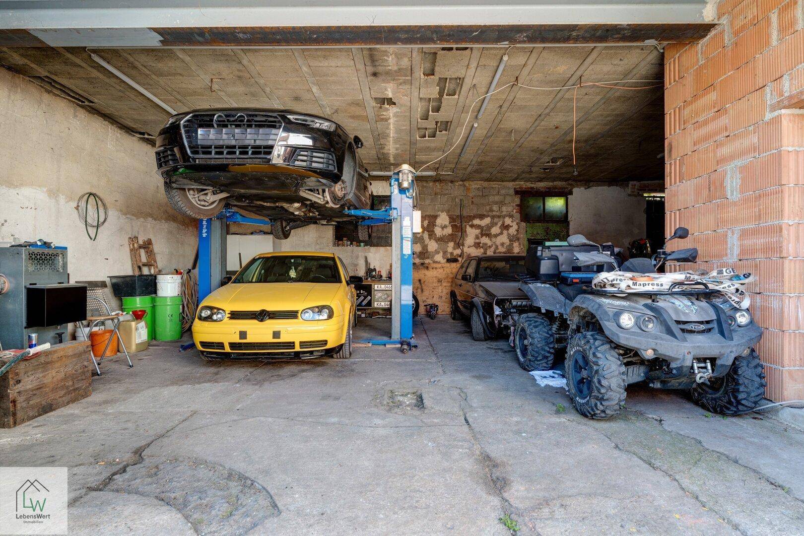 Geräumige Garage oder Werkstatt mit Hebebühne, einem Auto und einem Quad für Reparaturen.