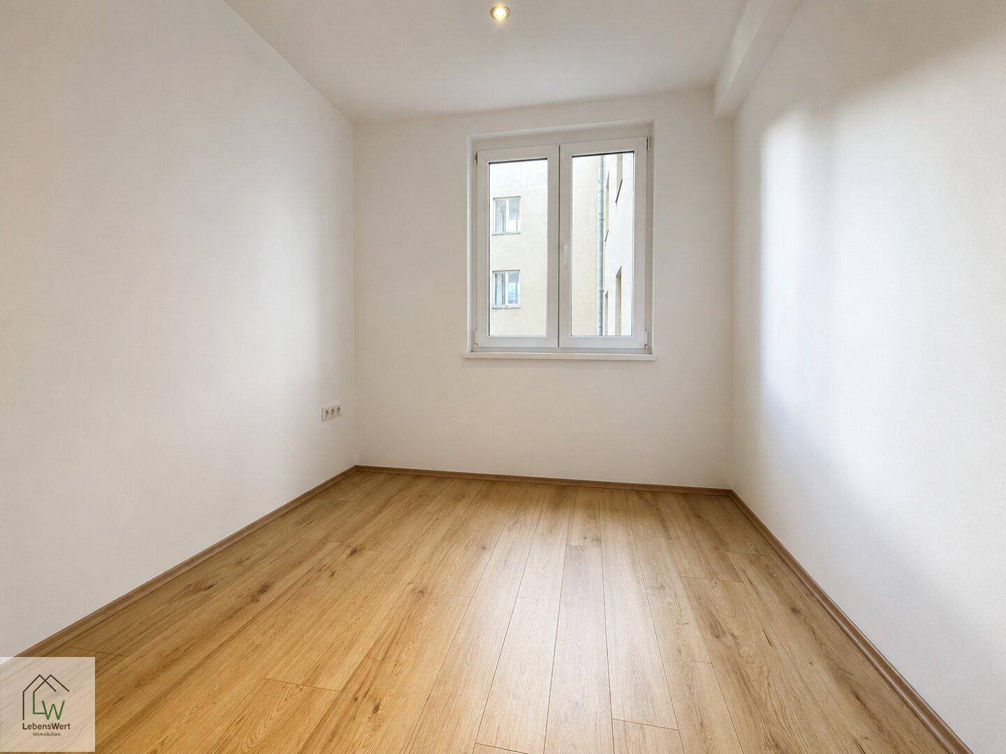 Kleinerer, heller Raum mit Laminatboden und Fenster, geeignet als Schlaf- oder Arbeitszimmer.