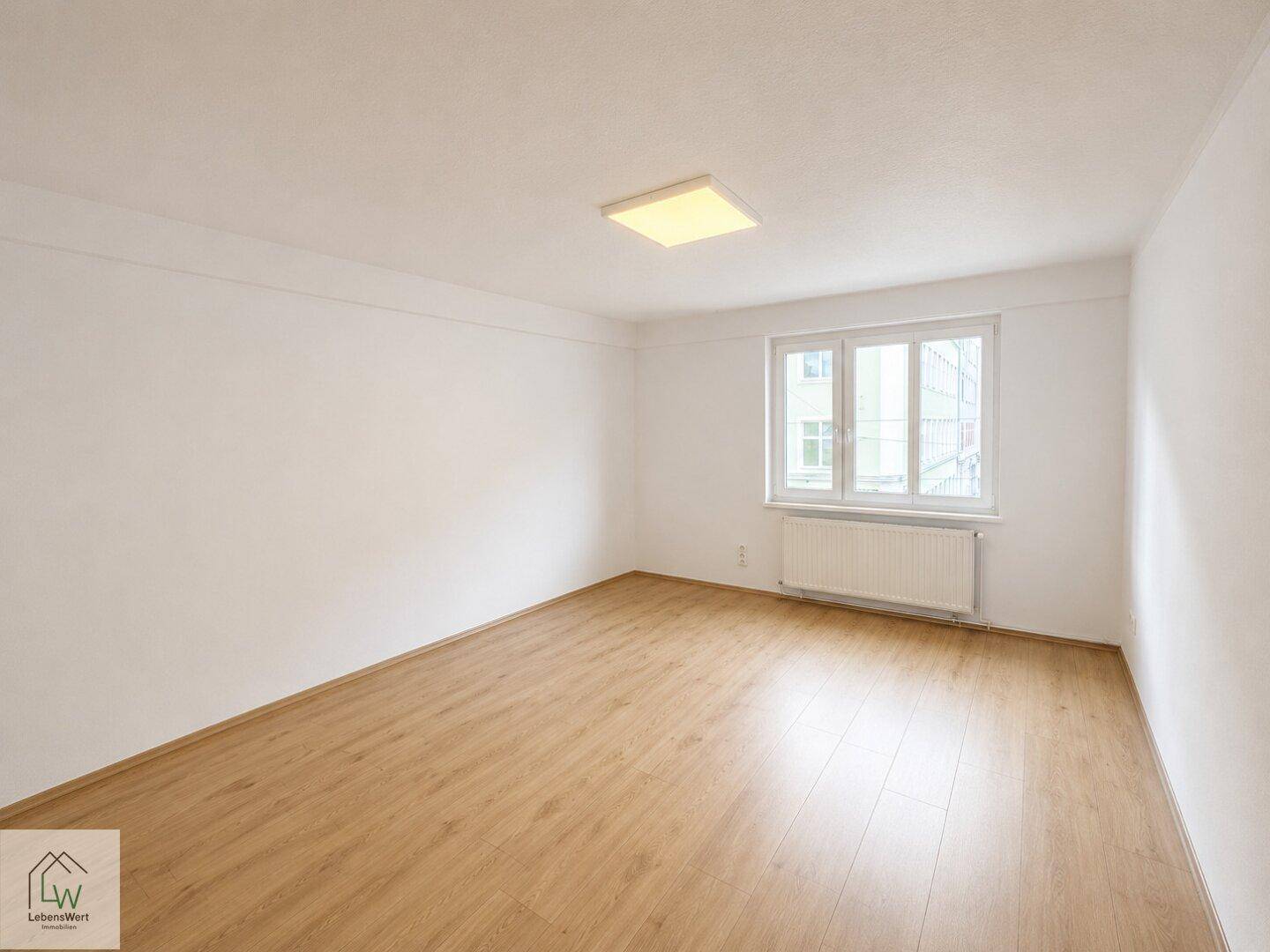 Weiterer heller Raum mit Laminatboden und Fenster, vielseitig nutzbar.
