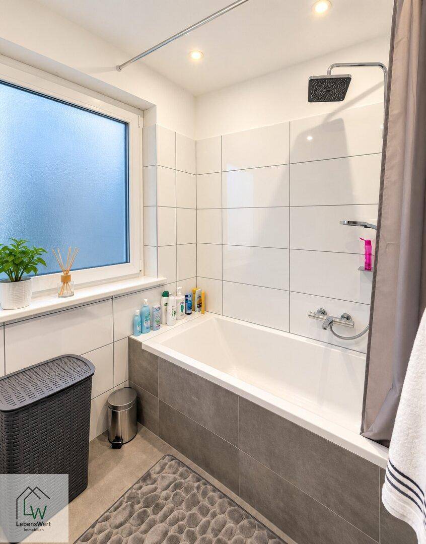 Modernes Badezimmer mit Badewanne, Regendusche und Fenster für natürliches Licht.
