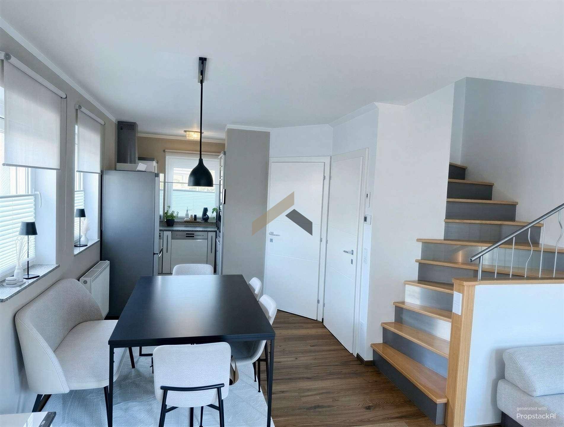 Heller Essbereich mit modernem Tisch, Sitzbank und Zugang zur Küche sowie Treppe.