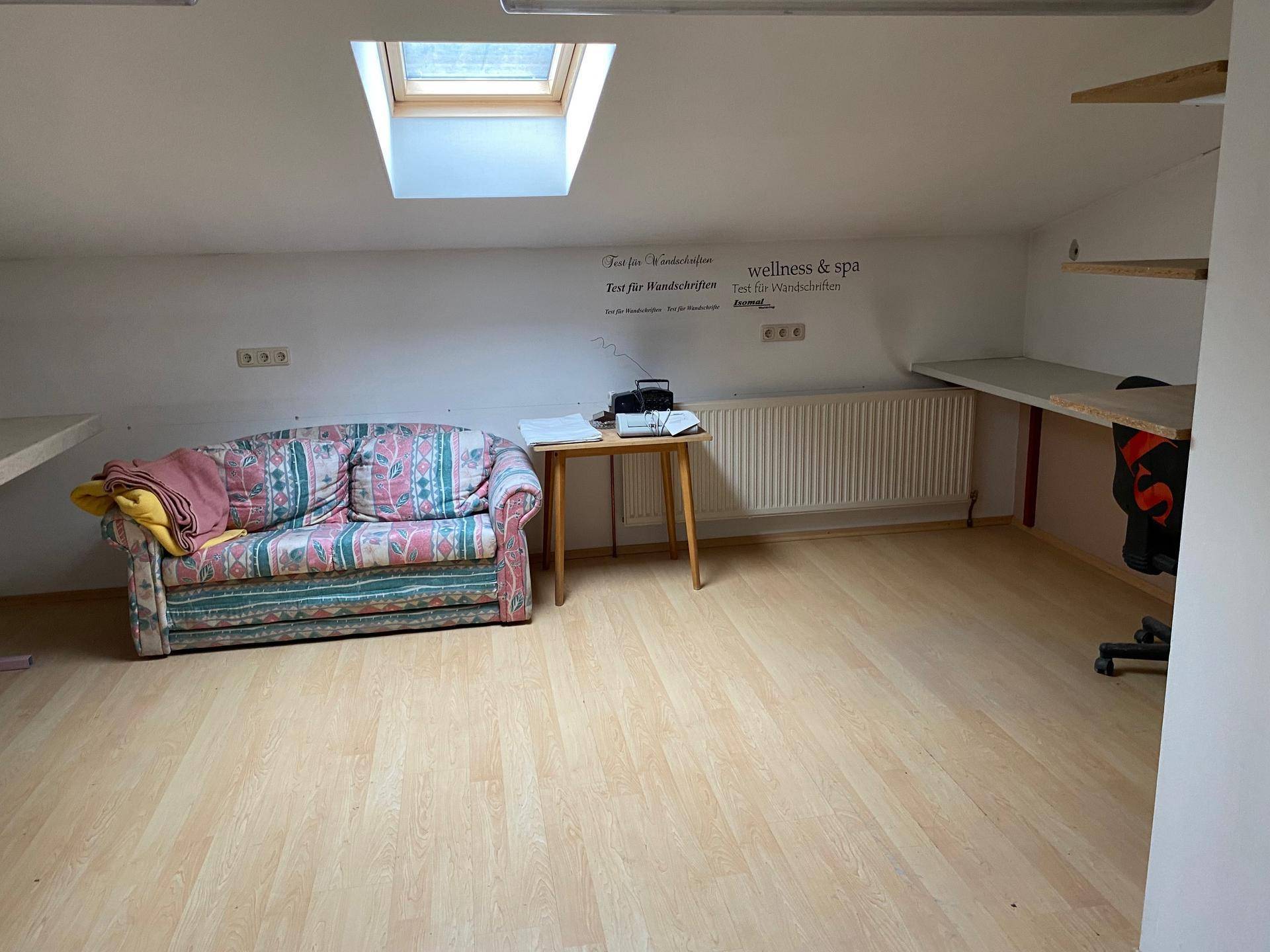Gemütlicher Dachraum mit Schrägen, einem Dachfenster und einem Sofa, ideal als Rückzugsort.