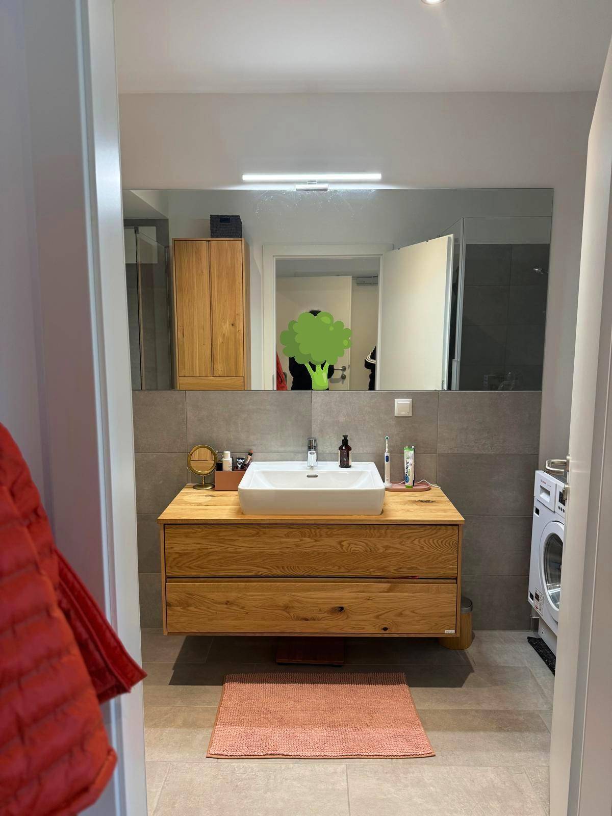 Modernes Badezimmer mit Holzwaschtisch, großem Spiegel und Waschmaschine.