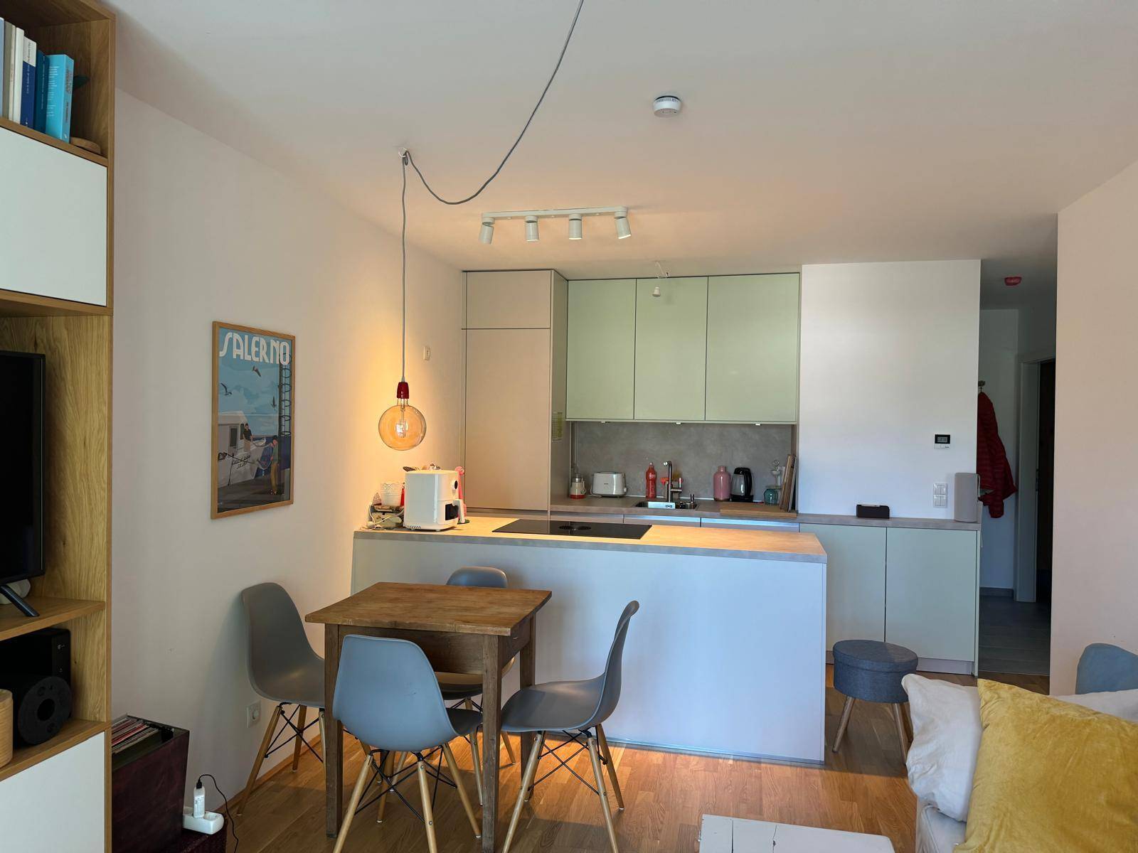 Offene Küche mit hellgrünen Schränken, Kochinsel und Essbereich im modernen Stil.