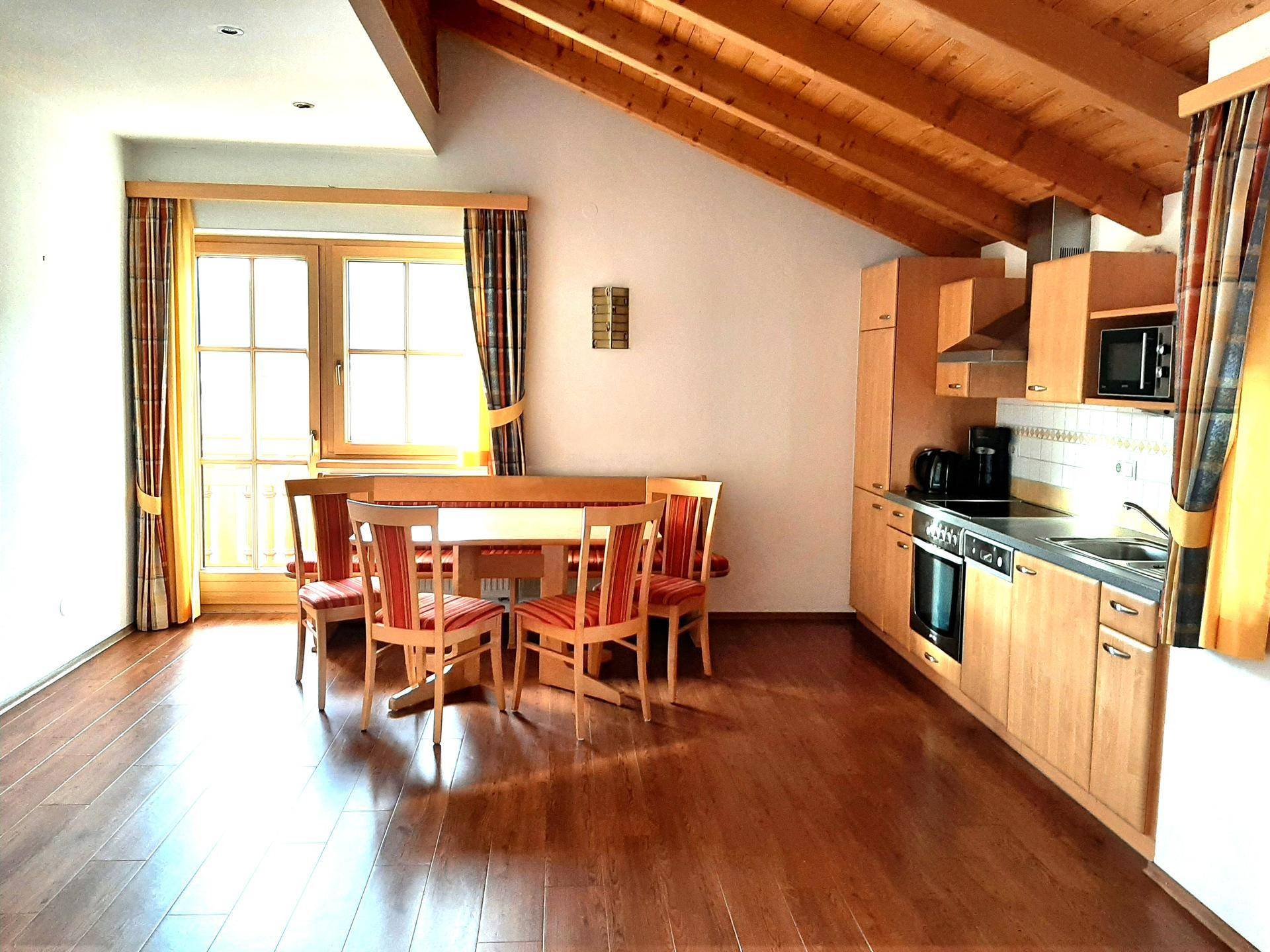 Offene Küche mit Essbereich, Holzbalkendecke und traditionellen Holzmöbeln unter Dachschräge.